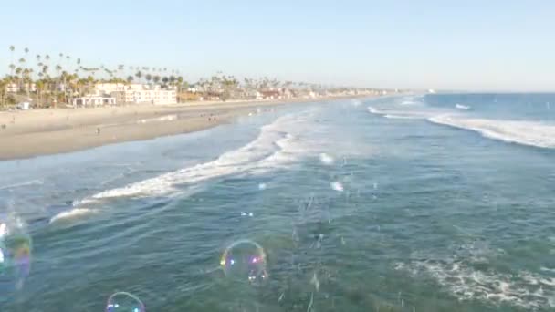 カリフォルニア州の桟橋上の石鹸泡、ぼやけた夏のシームレスなループの背景。創造的なロマンチックな隠喩、夢、幸福と魔法の概念。子供時代、ファンタジー、自由の抽象的なシンボル — ストック動画