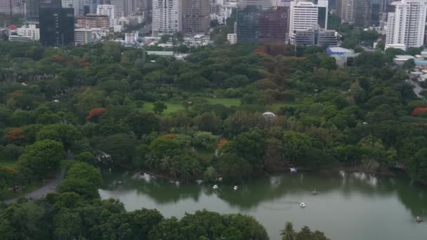 Zielony park w metropolii. Drone widok zielonych drzew Lumphini Park w pobliżu drogi i wysokich budynków na ulicach Bangkoku, Tajlandia — Wideo stockowe