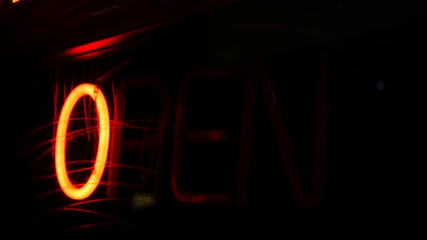 Open neon sign glowing in the dark. Vivid retro styled text at entrance on glass window. Colorful electric banner selective focus close up. Light bulbs radiance at night. Shiny illuminated lettering — Stock Video