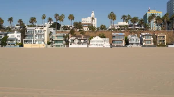 California lato plaża estetyczne, słoneczne błękitne niebo, piasek i wiele różnych domów nad morzem weekendowych. Budynki nadmorskie, nieruchomość w Santa Monica Pacific Ocean Resort w pobliżu Los Angeles CA USA — Wideo stockowe