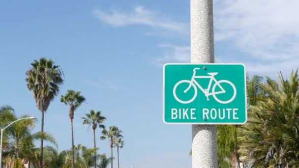 Ruta en bicicleta verde señal de tráfico en California, Estados Unidos. Bicicleta carril singpost. Bicicleta en Oceanside complejo turístico pacífico. Letrero de carril bici y palma. Estilo de vida saludable, recreación y seguridad símbolo de ciclismo — Vídeo de stock