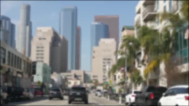 Rijden in de binnenstad straten van Los Angeles, Californië, USA. Defocked zicht van auto door glazen voorruit op de oprit. Wazige weg met voertuigen in Hollywood. Camera binnen auto, LA stad esthetische — Stockvideo