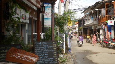 SAMUI Adaları, THAILAND - 27 Mayıs 2019: Balıkçı Köyü 'nde hediyelik eşya dükkanları olan tipik turistik cadde. Gündüz vakti Asya 'da sakin bir şehir manzarası ve turistik dükkanlar. Motosikletli Taylandlılar
