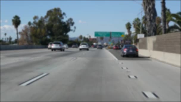 Fahren auf dem Intercity-Freeway in Los Angeles, Kalifornien USA. Defokussierter Blick aus dem Auto durch die gläserne Windschutzscheibe auf der viel befahrenen Autobahn. Verschwommene Vororteinfahrt mit mehreren Fahrspuren. Kamera im Auto in LA — Stockvideo
