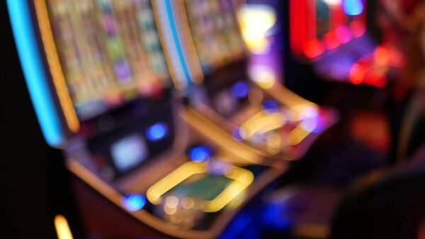 Defocused slot machines glow in casino on fabulous Las Vegas Strip, USA. Blurred gambling jackpot slots in hotel near Fremont street. Illuminated neon fruit machine for risk money playing and betting.