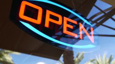 Karanlıkta parlayan açık neon ışığı. Cam pencerenin girişinde canlı retro stil metin var. Renkli elektrikli pankart seçici odaklanma. Ampuller gece parlıyor. Parlak parlak harfler.