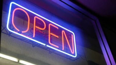 Karanlıkta parlayan açık neon ışığı. Cam pencerenin girişinde canlı retro stil metin var. Renkli elektrikli pankart seçici odaklanma. Ampuller gece parlıyor. Parlak parlak harfler.