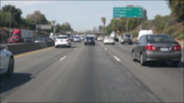 Los Angeles, Kaliforniya 'da şehirlerarası otobanda araba sürüyorum. Yoğun otoyoldaki arabanın cam ön camından odaklanmış görüntüsü. Bulanık banliyö yolu. Kamera Los Angeles 'ta.