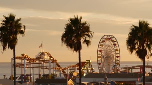 Классическое колесо обозрения, парк аттракционов на пляже в Санта-Монике. Летнее время California aesthetic, iconic view, symbol of Los Angeles, CA USA. Закат золотое небо и достопримечательности — стоковое видео