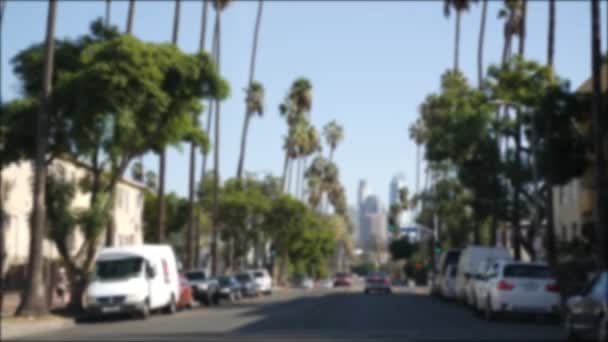 Rijden in de binnenstad straten van Los Angeles, Californië, USA. Defocked zicht van auto door glazen voorruit op de oprit. Wazige weg met voertuigen in Hollywood. Camera binnen auto, LA stad esthetische — Stockvideo