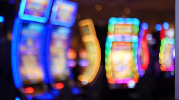 Defocused slot machines glow in casino on fabulous Las Vegas Strip, USA. Blurred gambling jackpot slots in hotel near Fremont street. Illuminated neon fruit machine for risk money playing and betting.