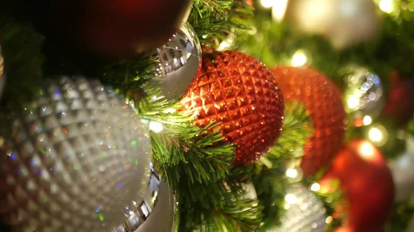 Closeup of Festively Decorated Outdoor Christmas tree with bright red balls on blurred sparkling fairy background. Defocused garland lights, Bokeh effect. Merry Christmas and Happy Holidays concept
