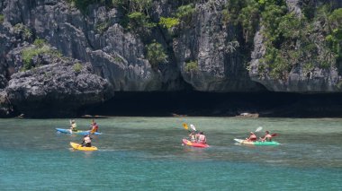 ANG ThON Marine Park, SAMUI, THAILAND - 9 HAZİRAN 2019: Bir grup turist mavi Idyllic turkuaz okyanus suyuyla kayalara yakın kayalarda kano sürerken kürek çekiyor.