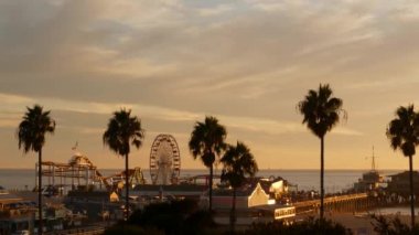 Klasik dönme dolap, Santa Monica Pasifik Okyanusu Sahili 'ndeki iskeledeki lunapark. Kaliforniya 'nın yaz zamanı estetik, ikonik manzara, Los Angeles' ın sembolü, CA USA. Günbatımı altın gökyüzü ve eğlence