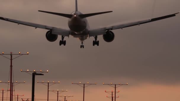 Samolot lądujący na lotnisku LAX o zachodzie słońca, Los Angeles, Kalifornia USA. Lot pasażerski lub sylwetka samolotu towarowego, dramatyczne zachmurzenie. Samolot przylatuje na lotnisko. Transport międzynarodowy — Wideo stockowe