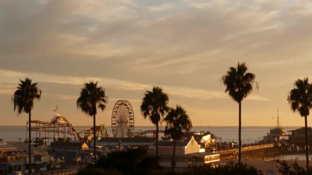 Klasszikus óriáskerék, vidámpark a Santa Monica-i mólón, óceánparti üdülőhely. Nyári kaliforniai esztétika, ikonikus kilátás, Los Angeles szimbóluma, CA USA. Sunset arany ég és látnivalók — Stock videók