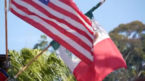 Mexikanska tricolor och amerikanska flaggan viftar på vinden. Två nationella ikoner i Mexiko och USA mot himlen, San Diego, Kalifornien, USA. Politisk symbol för gräns, relation och samhörighet — Stockvideo