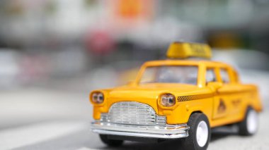 Sarı, boş, mini taksi, Harmon köşesi, Las Vegas, ABD. Odaklanamayan arka planda küçük bir eski araba modeli. Yumuşak odak noktasında ulaşım sembolü olarak küçük ikonik otomobil oyuncağı. Bulanık alışveriş merkezi.