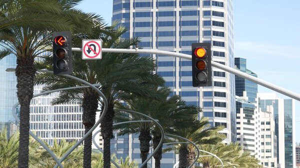Traffic light and caution sign, road intersection in USA. Transportation safety, rules and regulations symbol. Driveway crossing attenion signal against modern urban cityscape, San Diego, California.