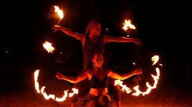 PHANGAN, THAILAND - 23 Şubat 2019 Tayland Fireshow. Yerel akrobatların yangın performansı. Ateşle tehlikeli numaralar. Sanatçılar karanlıkta ışıklarla dans eder, turistler için eğlence. Erkek ve kadın.