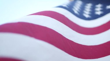 Rüzgarda dalgalanan Amerikan bayrağının yumuşak odak noktası. Yıldızlar ve Şeritler demokrasisi, vatanseverlik, özgürlük ve Bağımsızlık Günü sembolü. Yıldızlarla bezeli bayrak, ulusal gurur ve özgürlük ikonu