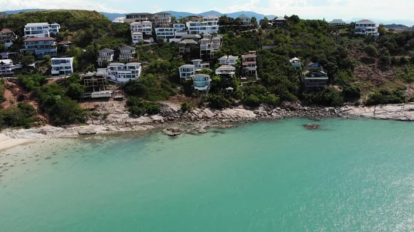 Green island with houses in ocean. Drone view of beautiful Ko Samui island in Thailand surrounded by turquoise water on sunny day