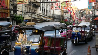 BANGKOK, THAILAND - 18 Mart 2019: Tuk tuks Asya şehrinde. Bangkok 'ta Çin Mahallesi' nin işlek caddesinde asfalt yolda giden renkli otomobil tribünleri.