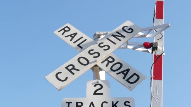 Plankorsningsvarningssignal i USA. Crossbuck meddelande och rött trafikljus på järnvägen korsning i Kalifornien. Säkerhetssymbol för järnvägstransporter. Varningsskylt om fara och tågspår — Stockvideo