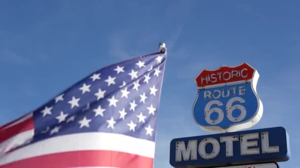 Motel retro sign on historic route 66 famous travel destination, vintage symbol of road trip in USA. Iconic lodging signboard in Arizona desert. Old-fashioned neon signage. National state flag waving — Stock Video