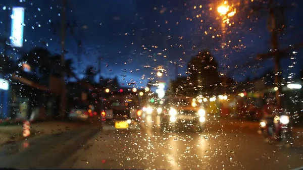 在雨季 带有灯光的泰国歌舞曲大巴沿着夜街行驶 从汽车的玻璃上俯瞰 典型的晚上亚洲的浪漫景象 暴风雨下的公共交通 — 图库照片