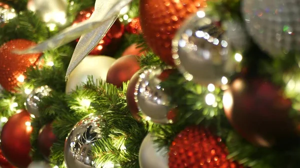 Closeup of Festively Decorated Outdoor Christmas tree with bright red balls on blurred sparkling fairy background. Defocused garland lights, Bokeh effect. Merry Christmas and Happy Holidays concept