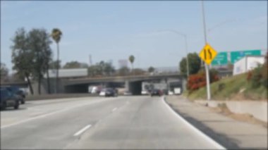 Los Angeles, Kaliforniya 'da şehirlerarası otobanda araba sürüyorum. Yoğun otoyoldaki arabanın cam ön camından odaklanmış görüntüsü. Bulanık banliyö yolu. Kamera Los Angeles 'ta.