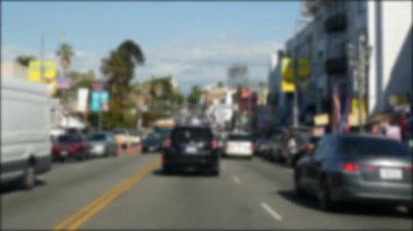 Los Angeles, Kaliforniya 'nın şehir merkezindeki caddelerde araba sürüyorum. Garaj yolundaki arabanın ön camından odaklı olmayan görüntü. Hollywood 'da araçları olan bulanık bir yol. Kamera otomobilin içinde, LA şehri estetiği.