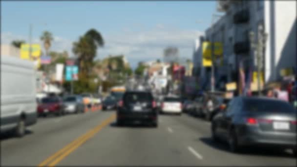 Driving on downtown streets of Los Angeles, California USA. Defocused view from car thru glass windshield on driveway. Blurred road with vehicles in Hollywood. Camera inside auto, LA city aesthetic — Stock Video