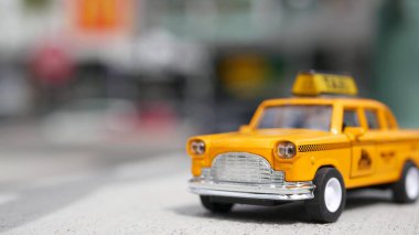 Sarı, boş, mini taksi, Harmon köşesi, Las Vegas, ABD. Odaklanamayan arka planda küçük bir eski araba modeli. Yumuşak odak noktasında ulaşım sembolü olarak küçük ikonik otomobil oyuncağı. Bulanık alışveriş merkezi.