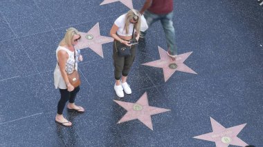 LOS ANGELES, CALIFORNIA, ABD - 7 NOV 2019: Los Angeles Hollywood Bulvarı 'nda şöhret yürüyüşü. Asfalt üzerinde ünlü yıldızların yanında yürüyen pedastrianlar. Dolby ve TCL Çin Tiyatrosu yakınlarındaki yürüyüş pisti..