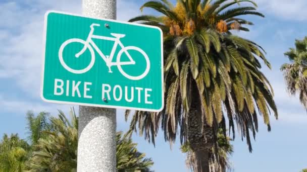 Moto Rota sinal de estrada verde na Califórnia, EUA. Bicicleta faixa singpost. Bikeway em Oceanside estância turística pacífica. Placa de ciclismo e palma. Estilo de vida saudável, recreação e segurança símbolo de ciclismo — Vídeo de Stock