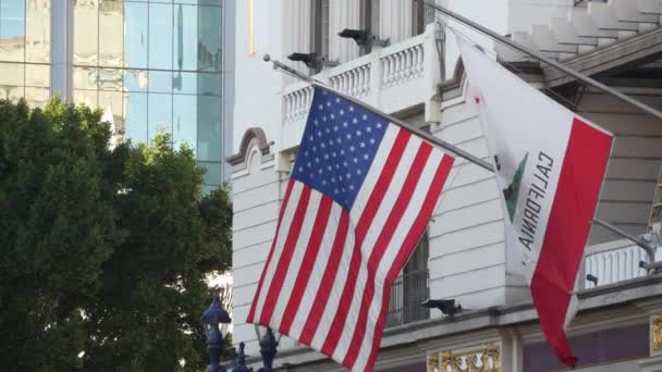 Flagi Kalifornii i Stanów Zjednoczonych machają na maszcie flagowym w Gaslamp, centrum San Diego. Godło Republiki i flagowy sztandar na sztandarze. Symbol ptryotyzmu i rządu — Wideo stockowe