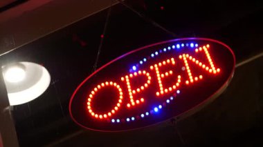 Karanlıkta parlayan açık neon ışığı. Cam pencerenin girişinde canlı retro stil metin var. Renkli elektrikli pankart seçici odaklanma. Ampuller gece parlıyor. Parlak parlak harfler.