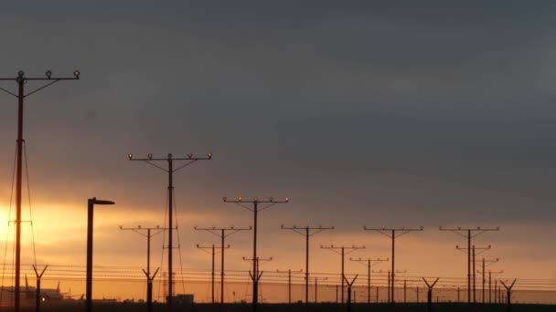 Repülőgép leszállás LAX repülőtér naplementekor, Los Angeles, Kalifornia USA. Utas- vagy teherszállító repülőgép sziluett, drámai felhős táj. Repülőgépek érkeznek a reptérre. Nemzetközi légi közlekedés — Stock videók