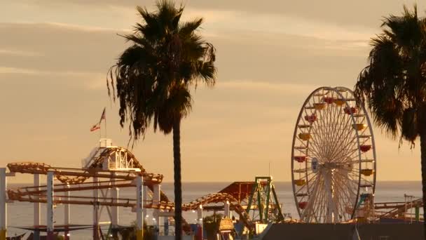 サンタモニカ・パシフィック・ビーチリゾートの桟橋にあるクラシック・観覧車、遊園地。夏のカリフォルニアの美学、象徴的な景色、ロサンゼルス、 CA USAのシンボル。夕日黄金の空とアトラクション — ストック動画