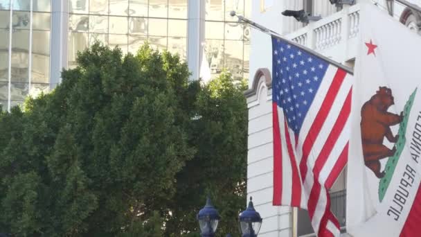 Flaggen Kaliforniens und der Vereinigten Staaten wehen an Fahnenmasten in Gaslamp, dem Zentrum von San Diego. Bären-Emblem der Republik und sternförmiges Banner am Fahnenstab. Symbol für Triotismus und Regierung — Stockvideo