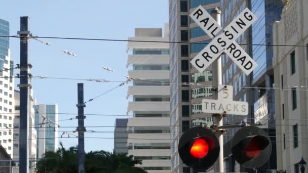 Señal de advertencia de cruce de nivel en EE.UU. Aviso cruzado y semáforo rojo en la intersección de carreteras ferroviarias en California. Transporte ferroviario símbolo de seguridad. Señal de precaución sobre el peligro y la vía del tren — Vídeo de stock