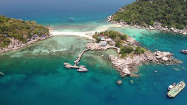 Küçük adaların yakınındaki tekneler ve rıhtımlar. Tayland 'da güneşli bir günde sahillere ve rıhtıma bağlı küçük adaların yakınında sakin mavi denizde yüzen motorlu dalış botları. Nang yuan koh tao