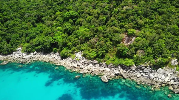 Calm sea near tropical volcanic island. Drone view of peaceful water of blue sea near stony shore and green jungle of volcanic Koh Tao Island on sunny day in Thailand