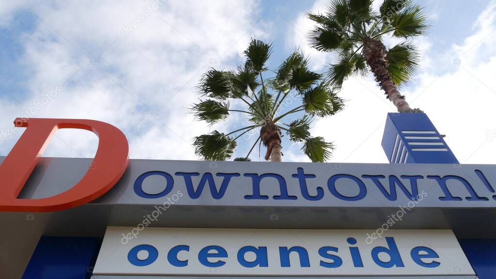 Oceanside nameboard sign and palm trees. Oside is the popular american tourist resort, pacific ocean west coast, San Diego County, California USA. Name of city of vacations and tourism on coastline.