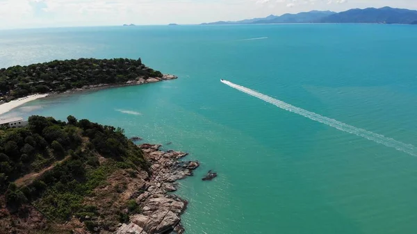 Beautiful ocean with track on water. Breathtaking aerial view of rocks, turquoise water and jet ski crossing ocean in Thailand. Drone view
