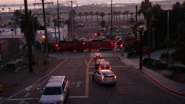 SAN DIEGO, CALIFORNIA USA - 15 HAZİRAN 2020: Uluslararası Lindbergh havaalanı yakınlarından geçiş. Gün batımında tren ve pist. MTS Tramvay taşımacılığı, arabalar ve demiryolu taşımacılığı.