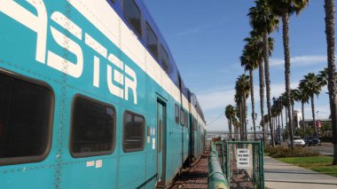SAN DIEGO, CALIFORNIA USA - 13 Şubat 2020: Coaster Commuter and palms, Amerika 'da toplu demiryolu taşımacılığı. Ekspres yolcu treni, Santa Fe ve Gaslamp yakınlarındaki demiryolu nakliyesi..