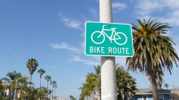 Moto Rota sinal de estrada verde na Califórnia, EUA. Bicicleta faixa singpost. Bikeway em Oceanside estância turística pacífica. Placa de ciclismo e palma. Estilo de vida saudável, recreação e segurança símbolo de ciclismo — Vídeo de Stock